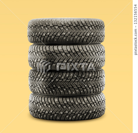 Four winter tires are stacked neatly in a tire shop. These studded tires are designed to provide excellent grip on icy roads, making vehicle safety a priority. 132156554