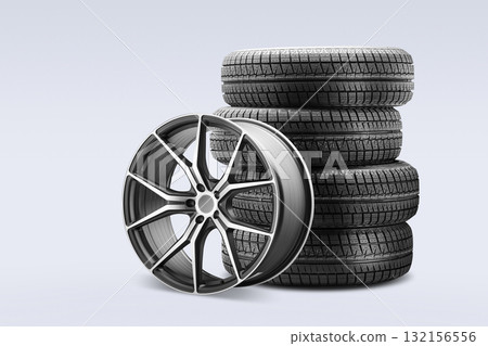 Four winter tires are stacked neatly next to a stylish alloy wheel, displaying options available for customers looking to purchase new tires at a contemporary tire store. 132156556