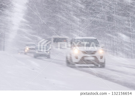 Vehicles Moving Through a Heavy Snowstorm on an Icy and Treacherous Road Condition, Cars are driving on a winter road in conditions of a severe winter snowstorm, snowfall and ice on roads with strong Vehicles Moving Through a Heavy Snowstorm on an Icy and Treacherous Road Condition, Cars are driving on a winter road in conditions of a severe winter snowstorm, snowfall and ice on roads with strong 132156654