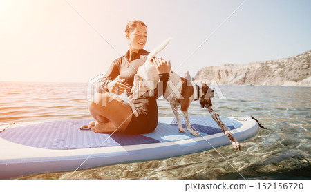 Woman Dog Paddleboarding Ocean - A woman and her dog are paddleboarding on a sunny day in the ocean. Woman Dog Paddleboarding Ocean - A woman and her dog are paddleboarding on a sunny day in the ocean. 132156720