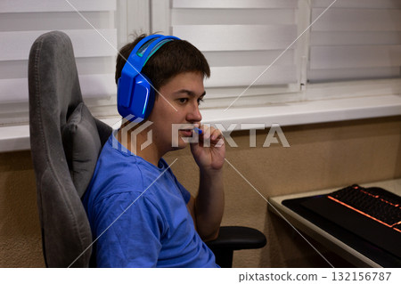 Gamer equipped with vibrant blue headphones, interacting through microphone. Moment captures essence of modern gaming culture, where communication plays key role in teamwork and strategy 132156787