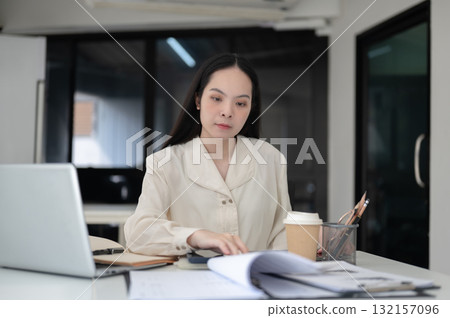 Businesswoman or female office worker is reading documents while sitting at working table in office. Businesswoman or female office worker is reading documents while sitting at working table in office. 132157096