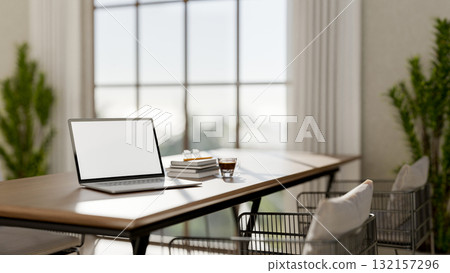 White screen laptop with books and coffee on table and steel armchairs in dining hall of restaurant. White screen laptop with books and coffee on table and steel armchairs in dining hall of restaurant. 132157296