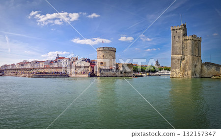 Panoramic view of the iconic entrance to the Vieux Port of La Rochelle, France. Panorama of all three medieval towers guarding the marina, the Tour Saint-Nicolas near the chain and the lantern towers Panoramic view of the iconic entrance to the Vieux Port of La Rochelle, France. Panorama of all three medieval towers guarding the marina, the Tour Saint-Nicolas near the chain and the lantern towers 132157347
