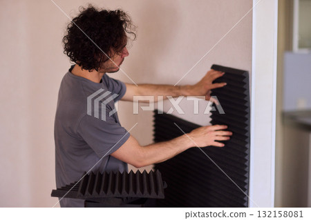 Setting up audio equipment with soundproofing panels in a modern studio environment Setting up audio equipment with soundproofing panels in a modern studio environment 132158081