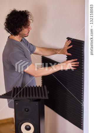 Setting up audio equipment with soundproofing panels in a modern studio environment Setting up audio equipment with soundproofing panels in a modern studio environment 132158083