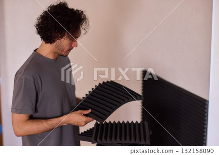 Setting up audio equipment with soundproofing panels in a modern studio environment Setting up audio equipment with soundproofing panels in a modern studio environment 132158090