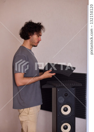 Setting up audio equipment with soundproofing panels in a modern studio environment Setting up audio equipment with soundproofing panels in a modern studio environment 132158120