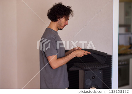 Setting up audio equipment with soundproofing panels in a modern studio environment Setting up audio equipment with soundproofing panels in a modern studio environment 132158122