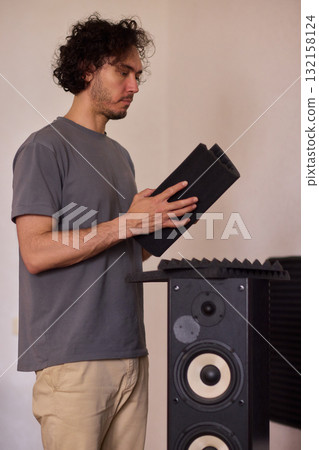 Setting up audio equipment with soundproofing panels in a modern studio environment Setting up audio equipment with soundproofing panels in a modern studio environment 132158124