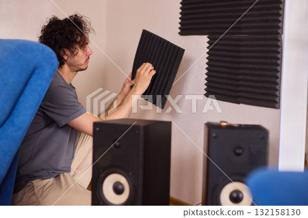 Setting up audio equipment with soundproofing panels in a modern studio environment 132158130