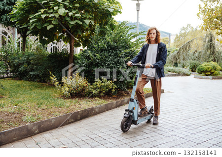 Young man riding an electric scooter in a park during a sunny afternoon 132158141