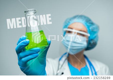 Scientist holding green liquid in laboratory during experimental medical research 132158289