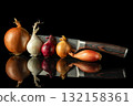 Various fresh onion types arranged with chef's knife on reflective black surface, perfect for culinary and cooking themes 132158361