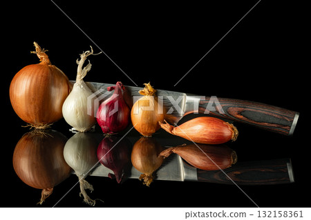 Various fresh onion types arranged with chef's knife on reflective black surface, perfect for culinary and cooking themes 132158361