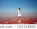 beautiful girl in white dress standing in pink water 132158882
