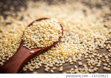 Roasted sesame seeds on spoon on wooden table. 132159621