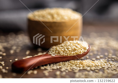 Roasted sesame seeds on spoon on wooden table. 132159622