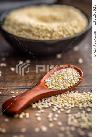 Roasted sesame seeds on spoon on wooden table. 132159623