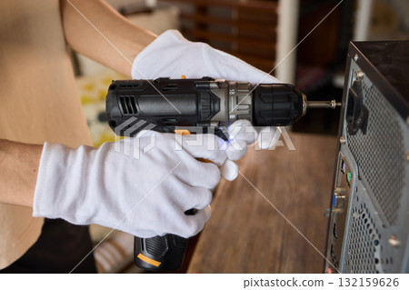 A Worker Skillfully Using a Power Drill for the Purpose of Computer Repair and Maintenance 132159626