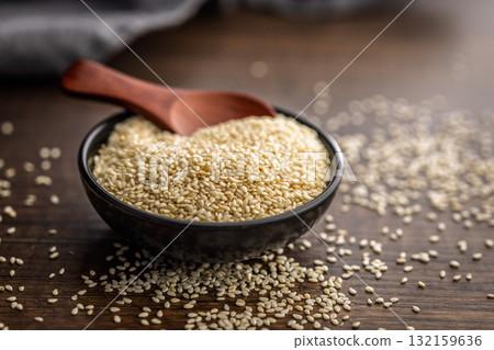 Roasted sesame seeds in bowl on wooden table. 132159636