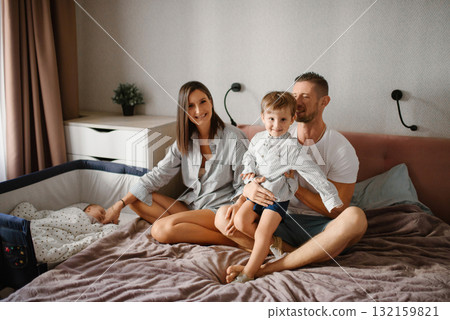 Smiling Family With Toddler And Newborn In Cozy Bedroom Smiling Family With Toddler And Newborn In Cozy Bedroom 132159821