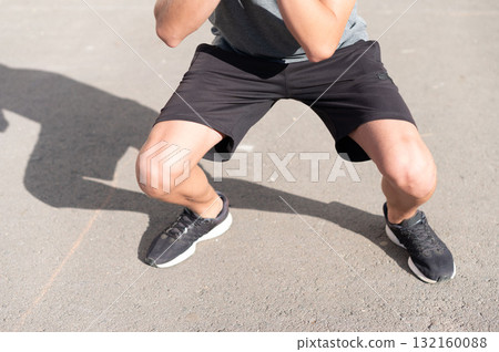 Teenager doing squats outdoors, focused and determined during his workout. Teenager doing squats outdoors, focused and determined during his workout. 132160088