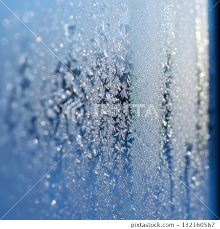 Frozen Window with Intricate Ice Crystal Patterns on Blue Background 132160567