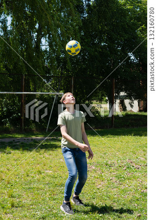 Teenager playing soccer outdoors, watching a ball in the air. 132160780
