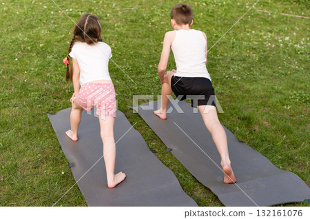 Kids practicing yoga outdoors on mats. A healthy and active lifestyle choice. Kids practicing yoga outdoors on mats. A healthy and active lifestyle choice. 132161076
