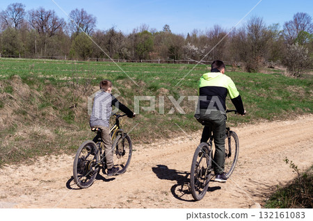 Father and son enjoy a sunny bike ride through a rural landscape. 132161083