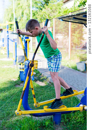 Boy exercising on outdoor fitness equipment. Healthy lifestyle and outdoor fun. Boy exercising on outdoor fitness equipment. Healthy lifestyle and outdoor fun. 132161088