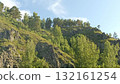 Lush Green Mountain Slope with Trees and Rocks Under a Bright Blue Sky, Scenic Landscape 132161254
