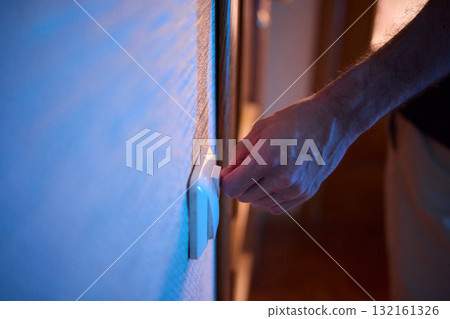 The action of a hand switching on a light in a dimly lit room creates a vibrant atmosphere 132161326