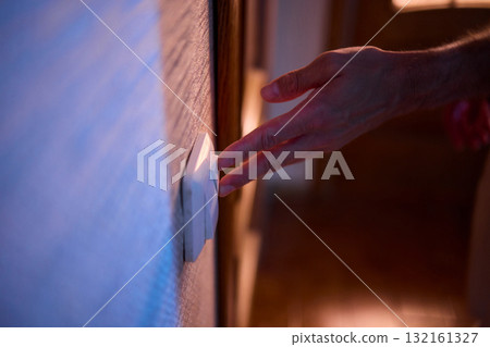 The action of a hand switching on a light in a dimly lit room creates a vibrant atmosphere 132161327