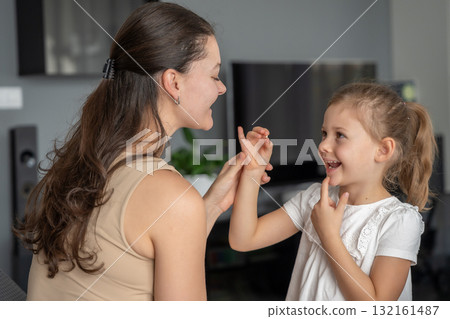 Little girl proudly shows her first lost baby tooth to her mom. Concept of childhood milestones, family bonding and emotional parenting moments. Focus on tooth Little girl proudly shows her first lost baby tooth to her mom. Concept of childhood milestones, family bonding and emotional parenting moments. Focus on tooth 132161487