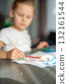 Milk tooth lying on table next to child drawing a picture for the tooth fairy. Capturing magical childhood traditions and creative emotional expression. 132161544