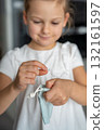 Little girl placing her baby tooth into a small pouch for the tooth fairy. Capturing a tender childhood ritual filled with imagination and meaning. 132161597
