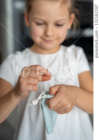 Little girl placing her baby tooth into a small pouch for the tooth fairy. Capturing a tender childhood ritual filled with imagination and meaning. Little girl placing her baby tooth into a small pouch for the tooth fairy. Capturing a tender childhood ritual filled with imagination and meaning. 132161597