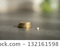 Close-up of a baby tooth lying in front of a stack of coins. Concept of tooth fairy tradition, childhood milestones and symbolic rewards. 132161598