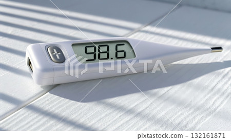 Digital thermometer displaying a temperature reading of 98.6 degrees on a bright surface 132161871