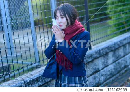 High school girls going to and from school for club activities on a cold day. High school students wearing winter clothes and carrying hand warmers. Going to and from school. Trimming. 132162069