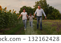 Happy family running together in nature, Joyful parents and child in the countryside, Family bonding in a sunflower field, Carefree moments with mom, dad, and kid, Parents and child enjoying outdoor 132162428