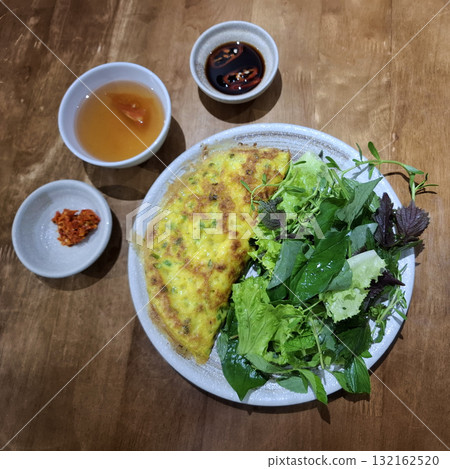 Vietnamese vegetarian banh xeo with fresh greens and sauces 132162520