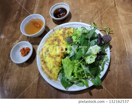 Vietnamese vegetarian banh xeo with fresh greens and sauces 132162537