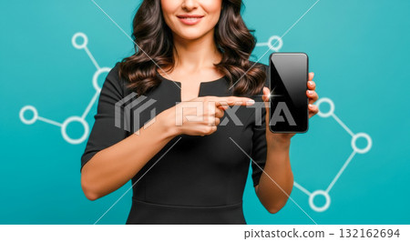 Smiling business woman pointing finger at smartphone with blank black screen, showing mobile app or website, isolated on turquoise background with network icons Smiling business woman pointing finger at smartphone with blank black screen, showing mobile app or website, isolated on turquoise background with network icons 132162694