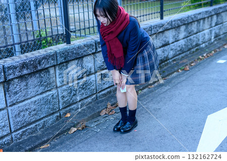 寒冷的一天，一名高中女生步行上下學，參加社團活動。她用熱敷袋敷在膝蓋上保暖。照片中她的膝蓋清晰可見。 132162724