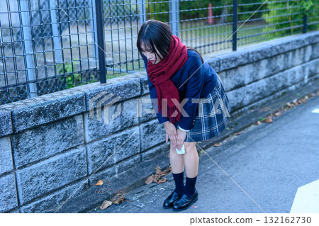 A high school girl goes to and from school on a cold day for club activities. She puts a heat pack on her knees while commuting to school. 132162730