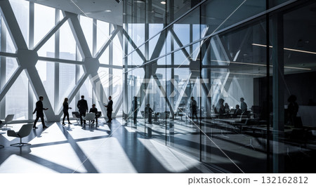 Modern corporate office interior with business people silhouettes in spacious sunlit lobby, contemporary architecture with large glass windows and deep shadows 132162812