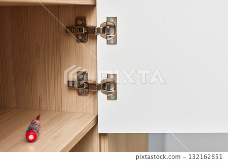 Modern and adjustable silver cabinet door hinges for furniture , with visible screws and hinge mechanism, close-up Modern and adjustable silver cabinet door hinges for furniture , with visible screws and hinge mechanism, close-up 132162851